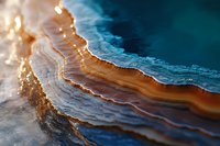 Macro photography of agate crystal slice showing detailed layers in blue and amber tones with natural light illuminating mineral structure and patterns.