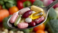 Colorful vitamin and supplement capsules on spoon with fresh fruits and vegetables background for healthy lifestyle and nutrition concepts.
