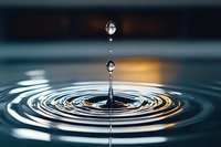Water droplet creating ripples on calm surface with golden light reflection and concentric circles in serene aquatic environment for wellness concepts.