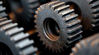 Macro shot of industrial metal gear wheels in dark setting, showing mechanical details and engineering precision with selective focus and textured surface.