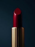 Luxury red lipstick with golden tube on dark background for cosmetics and beauty advertising campaigns.