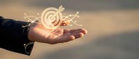 Businessman hand holding glowing target with arrows symbol representing goal achievement and strategic planning for business success and marketing objectives.