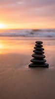 Zen stone stack on beach at sunset with golden sky reflection on wet sand creating peaceful meditation atmosphere for wellness and mindfulness concepts.