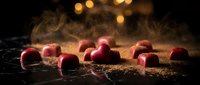 Red apples dusted with powder on dark surface with warm bokeh lighting, suitable for food photography, culinary content, and commercial advertising projects.