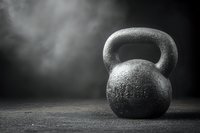 Heavy iron kettlebell on dark background with dramatic lighting and smoke effect, symbolizing strength training and fitness challenge.