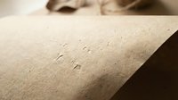 Close-up of water droplets on brown kraft paper surface with soft lighting and shallow depth of field for packaging and eco-friendly design concepts.
