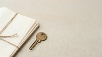 Vintage brass key and open notebook with twine on neutral beige background, suitable for security, access, and business concepts.