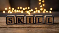 Wooden blocks spelling skill on rustic surface with warm bokeh lights in background, representing professional development and competency building for training materials.