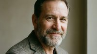 Mature Caucasian businessman with gray beard smiling confidently in professional suit jacket for corporate headshot and executive portrait photography.