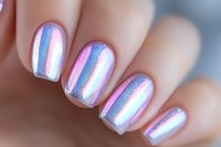 Holographic nail polish in pink and blue iridescent shimmer creates magical unicorn effect on manicured fingernails, macro beauty shot showing trendy chrome finish.