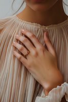 Female hand with gold ring resting on chest, wearing pleated white romantic blouse, soft natural lighting creates intimate atmospheric mood.
