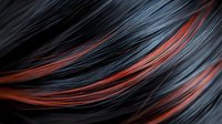 Close-up view of black hair with vibrant copper red highlights showing smooth, silky texture and flowing strands against dark background. Modern hairstyle trends.