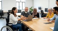 Diverse business team meeting with disabled woman leader presenting on laptop in modern office conference room for corporate collaboration and inclusion.