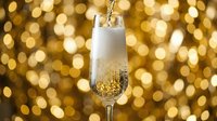 Champagne pouring into a flute glass against a golden bokeh background, ideal for celebrations, New Year's Eve, weddings, and festive occasions.
