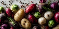 Fresh organic root vegetables and brussels sprouts on rustic background, colorful farm produce for healthy cooking.