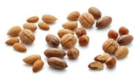 Mixed nuts collection with almonds walnuts hazelnuts and pecans scattered on white background for healthy snacking and cooking recipes.