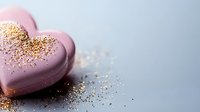 Pink heart-shaped chocolate candy with golden glitter sprinkled on top against gray background, romantic dessert for Valentine's Day celebration or sweet treats.