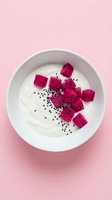 White bowl filled with creamy yogurt topped with vibrant magenta dragon fruit cubes and black seeds on soft pink background, suitable for food blogs and wellness content.