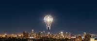 Giant glowing light bulb floating above downtown city skyline at night representing innovation, creativity and bright ideas for business concepts.