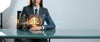 Professional businesswoman in suit holding glowing digital justice scales with network connections, representing legal technology and modern law practice.