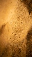 Golden textured clay wall surface with natural cracks and weathered patterns creating warm earthy background for rustic interior design projects.