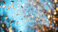 Festive gold confetti and glitter particles floating against blurred blue background with bokeh lights, creating magical celebratory atmosphere.