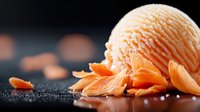 Creamy orange sherbet scoop with delicate citrus peel curls scattered on dark textured surface, dramatic side lighting creates gourmet dessert atmosphere.