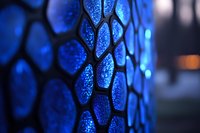 Glowing blue hexagonal pattern with water droplets creates dramatic macro photography effect, highlighting texture and depth through selective focus and bokeh lighting.