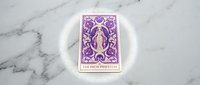 Purple ornate tarot card with female figure in decorative frame on marble surface for spiritual readings and mystical practices.
