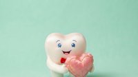 Cute cartoon tooth character holding pink heart on mint green background for dental care and oral health awareness campaigns.