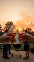Two hands toasting with beer glasses at golden hour sunset, outdoor celebration with warm lighting and silhouetted trees for friendship and social gatherings.