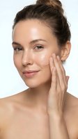 Young Caucasian woman applying moisturizer cream to face with gentle touch, natural glowing skin, daily skincare routine for healthy complexion and beauty care.