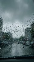 Raindrops on car windshield during storm with dramatic cloudy sky creating moody atmospheric driving conditions and weather patterns.