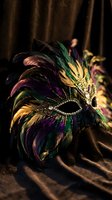 Ornate carnival mask with colorful feathers and gold details on luxurious fabric for masquerade ball, theater performance, or festive celebration decoration.