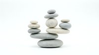 Balanced stacks of smooth gray pebbles arranged in a zen composition on a white background, symbolizing harmony and mindfulness.