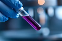 Laboratory gloved hand holding test tube with purple liquid against blurred scientific background with bokeh lights. Medical research concept.