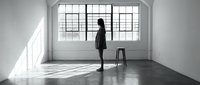 Young woman in business attire standing in empty modern loft space with large windows, concrete floor, and natural light for corporate, real estate, or lifestyle concepts.