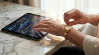 Professional businessman analyzing financial data and stock market charts on digital tablet for investment decisions and trading strategies.