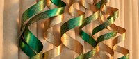Elegant green and gold ribbons flowing gracefully on warm beige background, creating luxurious festive decoration for holiday celebrations and gift wrapping.