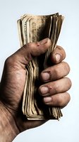 Hand holding stack of aged currency notes, displaying worn paper money bundle. Concept for finance, wealth, savings, investment, banking, and economic themes.