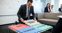 Professional businessman assembling colorful puzzle pieces labeled sales, marketing, technology and business in modern office meeting room.