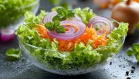Fresh mixed salad with lettuce, red onion rings, cherry tomatoes and herbs in glass bowl on dark surface for healthy eating and nutrition.