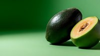Fresh ripe avocado cut in half showing creamy flesh and pit on green gradient background for healthy eating and nutrition concepts.