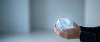 Hands of a businessman holding a glowing crystal ball, symbolizing future vision, prediction, and innovation in business strategy.