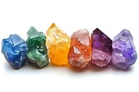 Raw healing crystals in rainbow colors arranged in row showing natural mineral formation with rough edges and translucent surfaces on white background.
