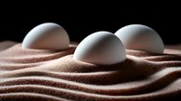 White eggs nestled in smooth waves of brown sand against dark background, creating minimalist zen-like composition for food or wellness concepts.