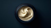 Luxurious face cream with smooth swirl texture in elegant black jar on dark background for skincare and beauty product marketing campaigns.