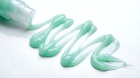 Transparent green gel or cosmetic product squeezed from container onto white surface, suitable for skincare, beauty, and wellness design projects.