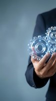 Businessman holding transparent glass gears in palm representing innovation, automation and digital transformation in modern business technology.