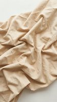 Crumpled beige linen fabric with natural folds and wrinkles on white background, suitable for textile, fashion, and interior design projects.